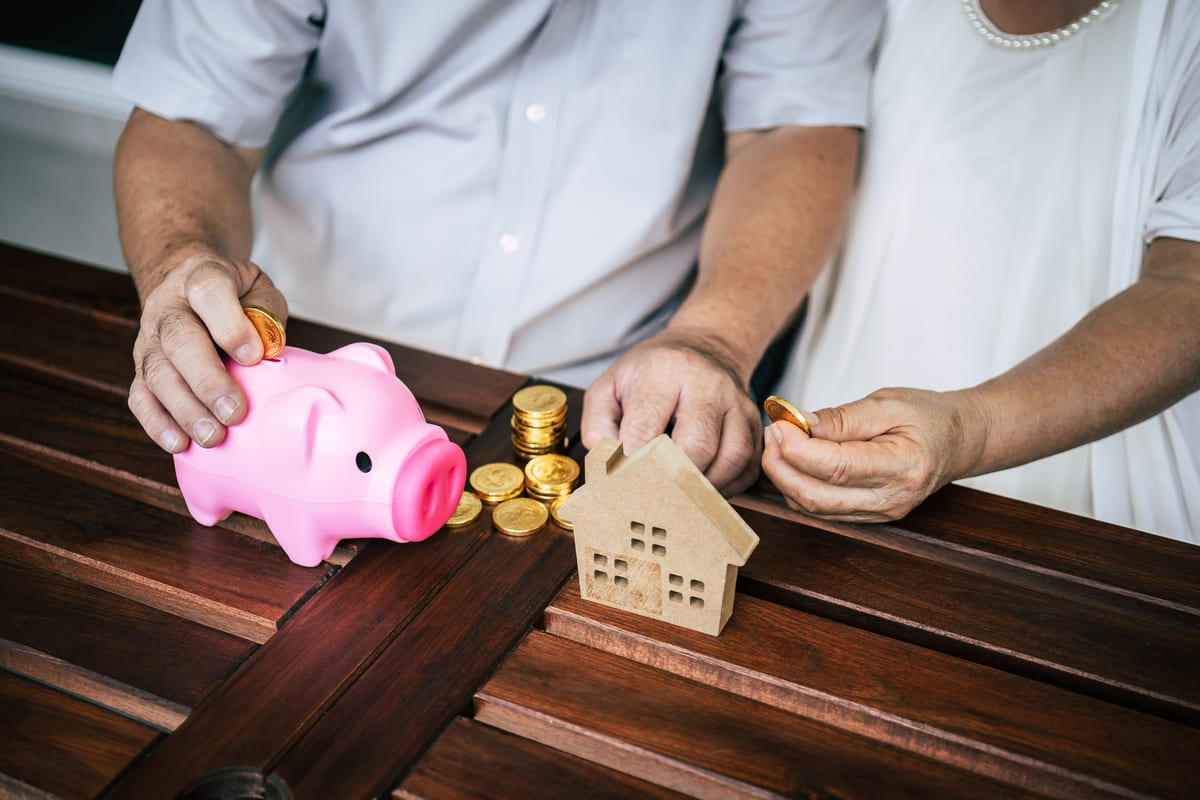 Parejas mayores hablando de finanzas con una alcancía